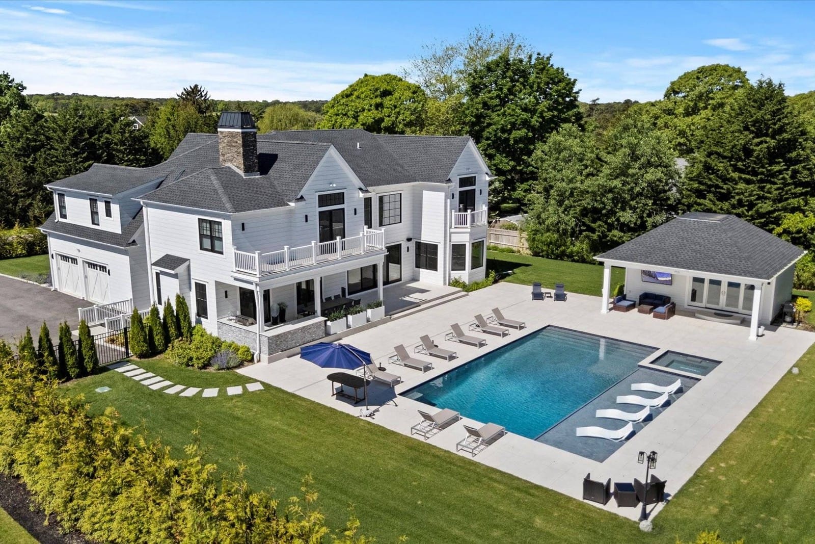 A white house with a gray roof and a pool, courtesy hamptonsre.com