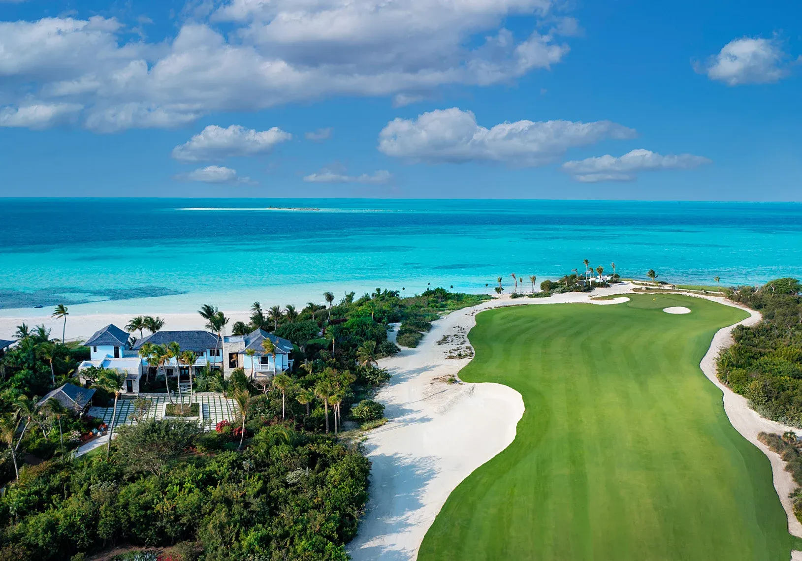 A golf hole running toward the ocean at Baker's Bay, with white sand bunkers and homes among the trees beside the fairway