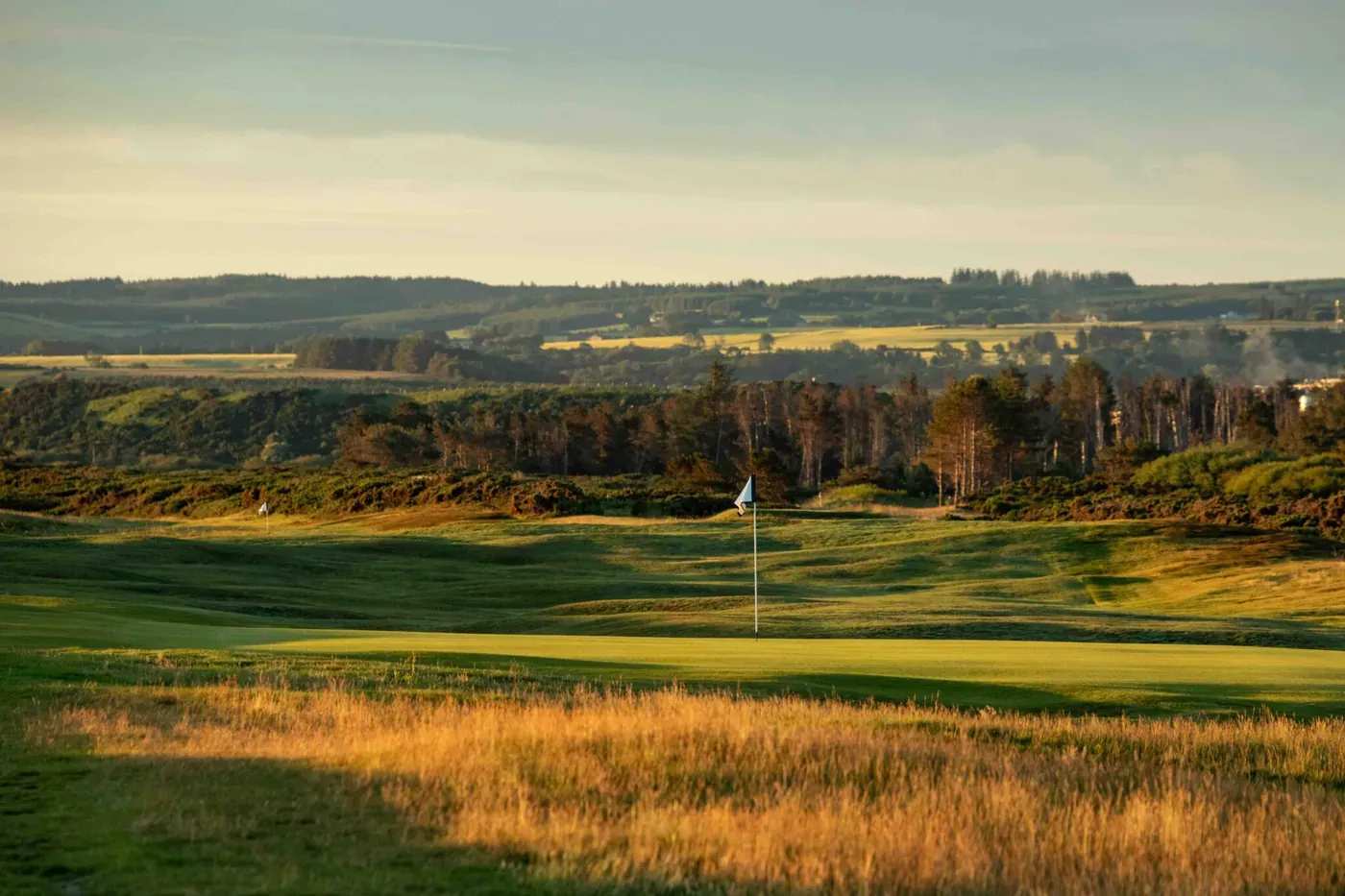 Spey Bay Golf Club under summer-solstice sunrise light on the Moray Coast in Scotland, fairways and dunes toward the firth.