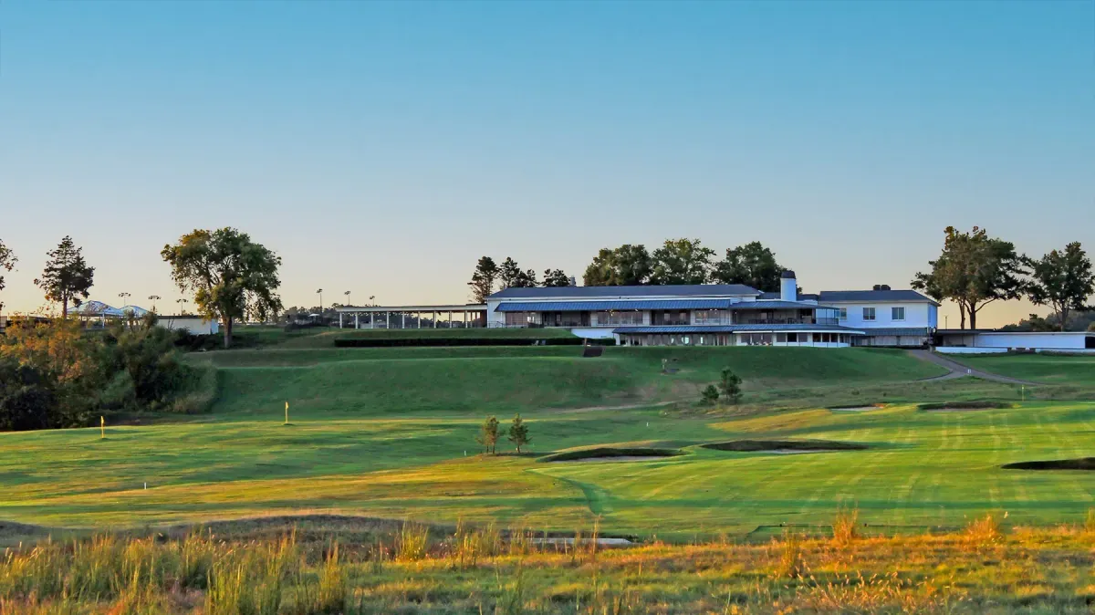 Landscape view of Old Natchez Country Club's white two-story clubhouse and veranda overlooking fairways at sunset in Franklin, Tennessee