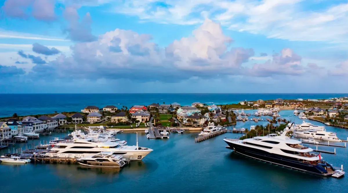 Aerial view of the Baker's Bay marina on Great Guana Cay with large yachts in the slips, the marina village behind, and the Atlantic beyond