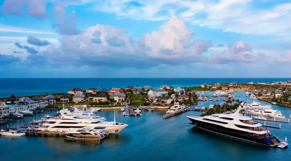 Aerial view of the Baker's Bay marina on Great Guana Cay with large yachts in the slips, the marina village behind, and the Atlantic beyond
