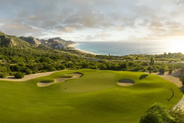Hole 3 green at Cabo Real in Los Cabos, with white sand bunkers in the foreground and the Pacific Ocean and coastline beyond