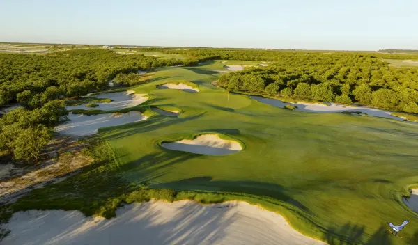 Aerial view of a green ringed by deep sand bunkers at High Grove in Venus, Florida, with citrus groves stretching to the horizon
