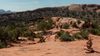 Hikers traverse the rugged Syncline Loop Trail in Canyonlands National Park, surrounded by red rock formations and desert vegetation.