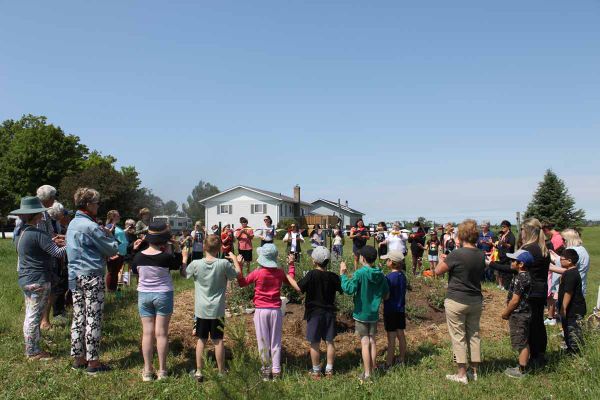 Students of Lakeview and CC McLean schools and members of the Western Manitoulin Community Garden gather in a group to listen