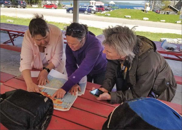 Norteast region coordinator for the Ontario Breeding Bird Atlas Anna Sheppard, center, pours over maps of Manitoulin Island w