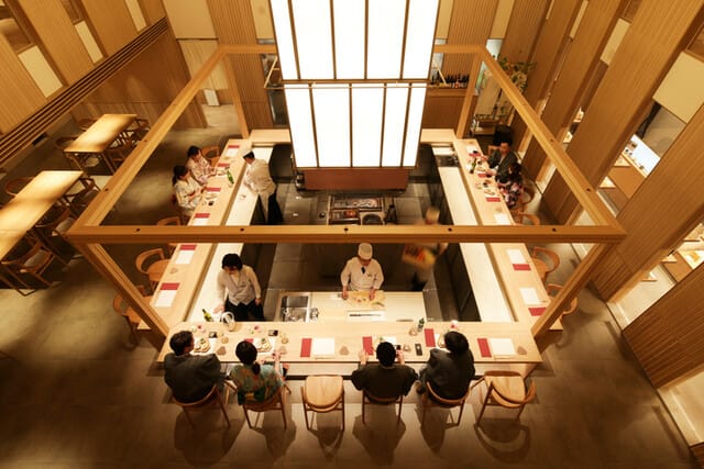西村屋的室內照片,它的天花板很高,顯得氣派。座位有霸台與一般桌子,霸台可以看師傅料理食材