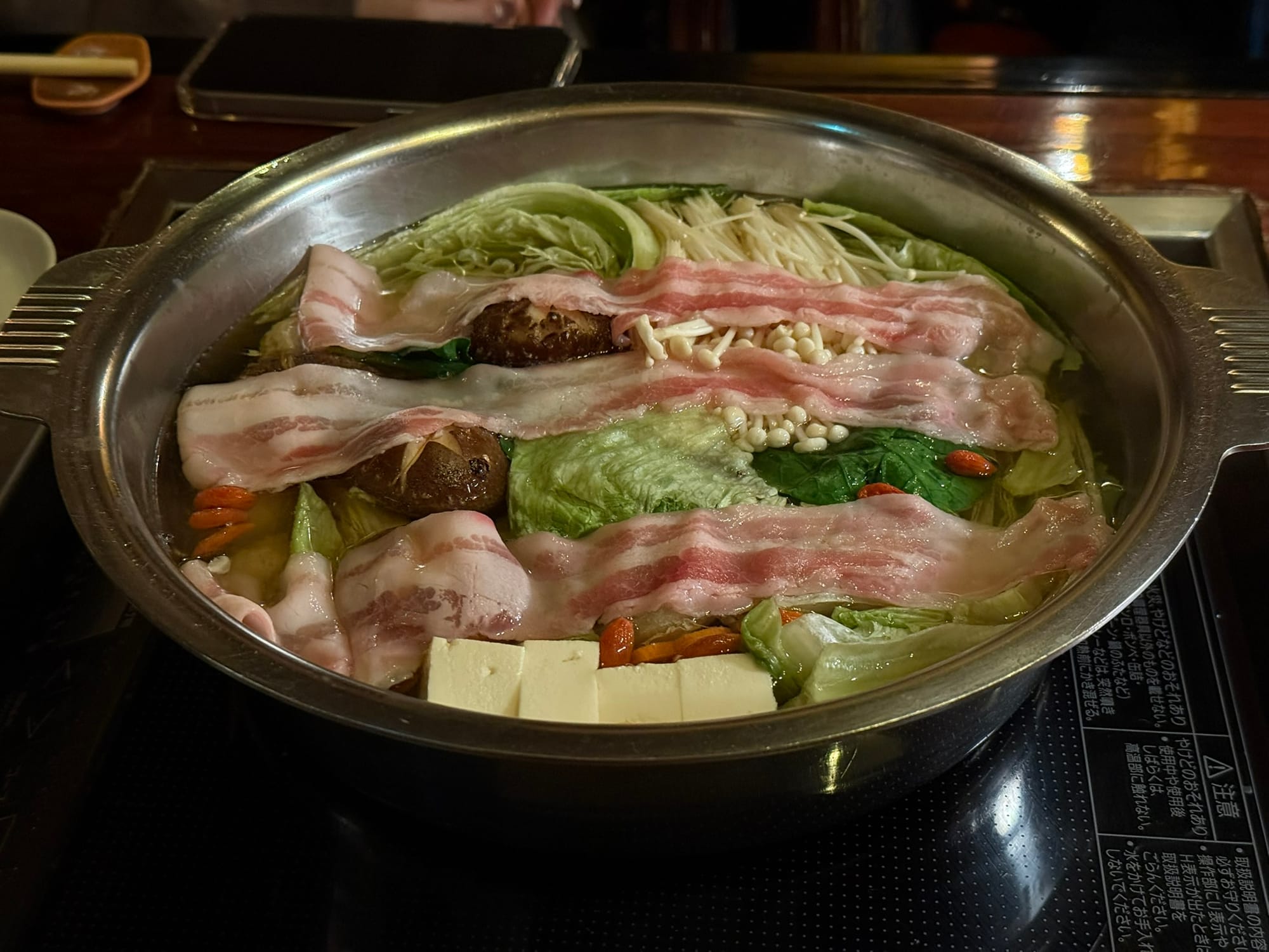 坐離宮山藥泥火鍋的烹煮過程，店員先將新鮮蔬菜、菇類與肉片放入高湯中燉煮的初始畫面。