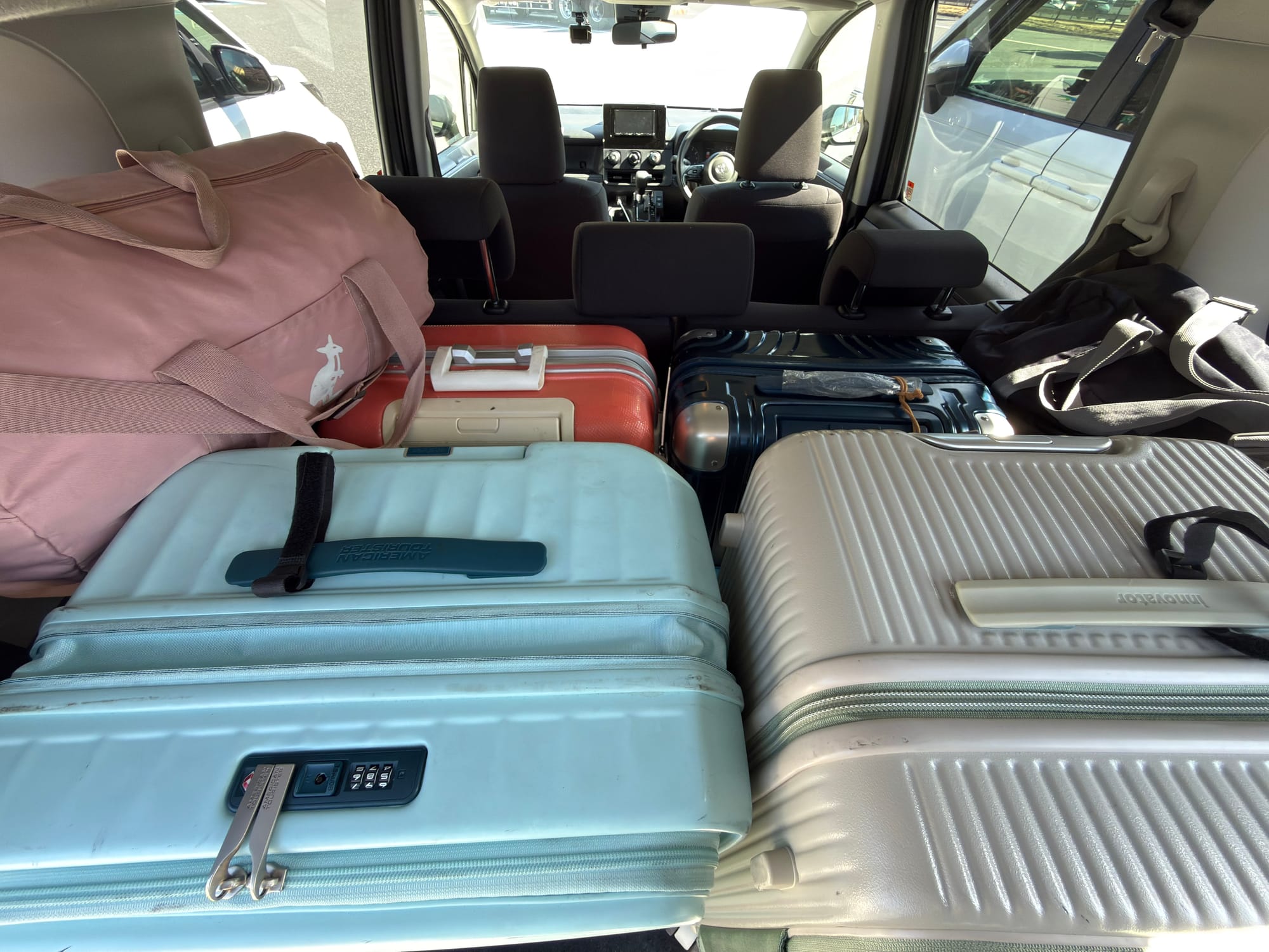 Toyota Sienta 四人滿載行李排列細節：4 個行李箱採直立放置，2 個手提行李放在左右兩側，高度剛好，不會擋到後視鏡的視線。