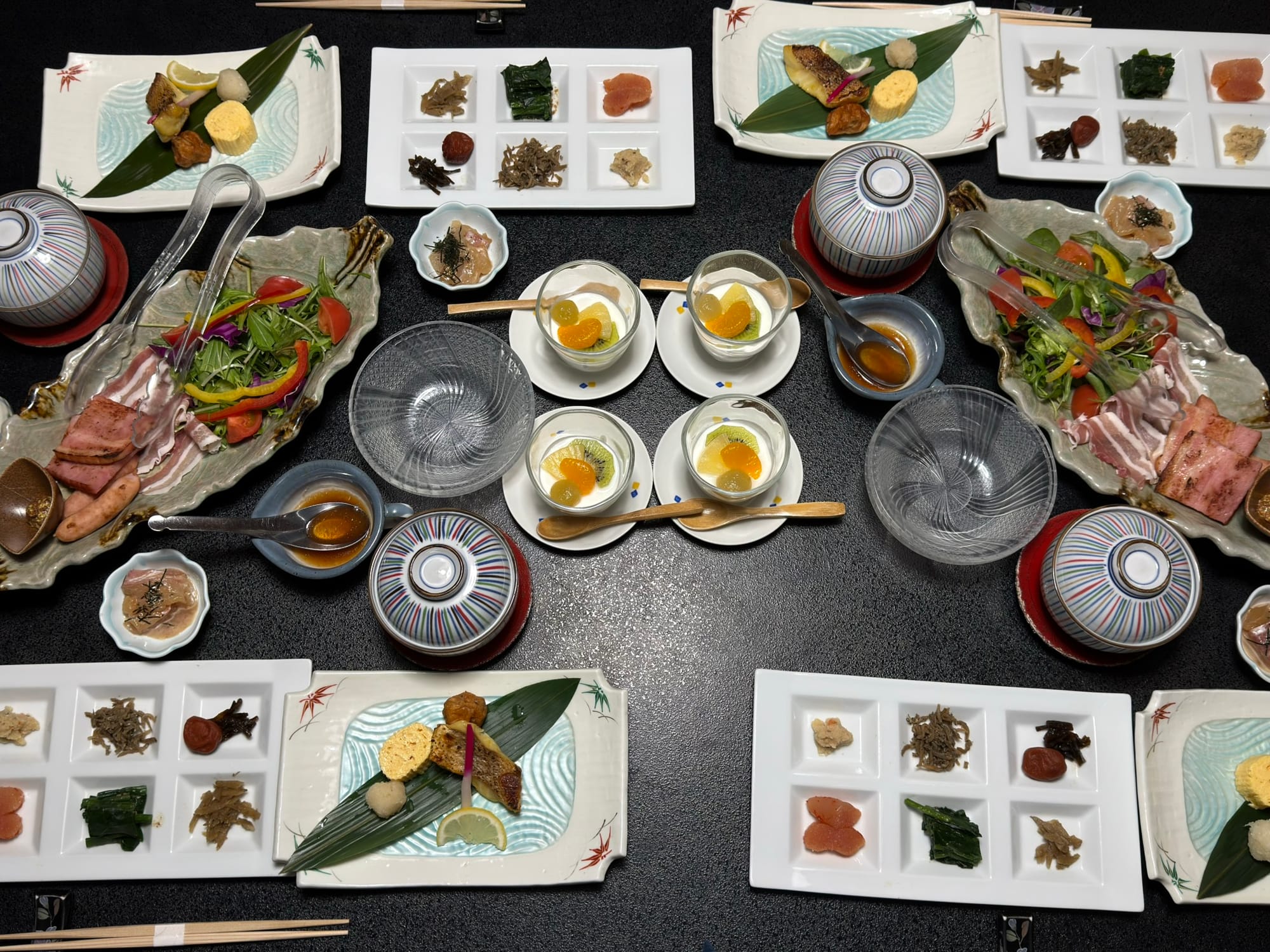 精緻日式定食早餐，包含豐富的日式小菜、魚肉、豆腐、新鮮沙拉與味噌湯，擺盤考究且份量十足。