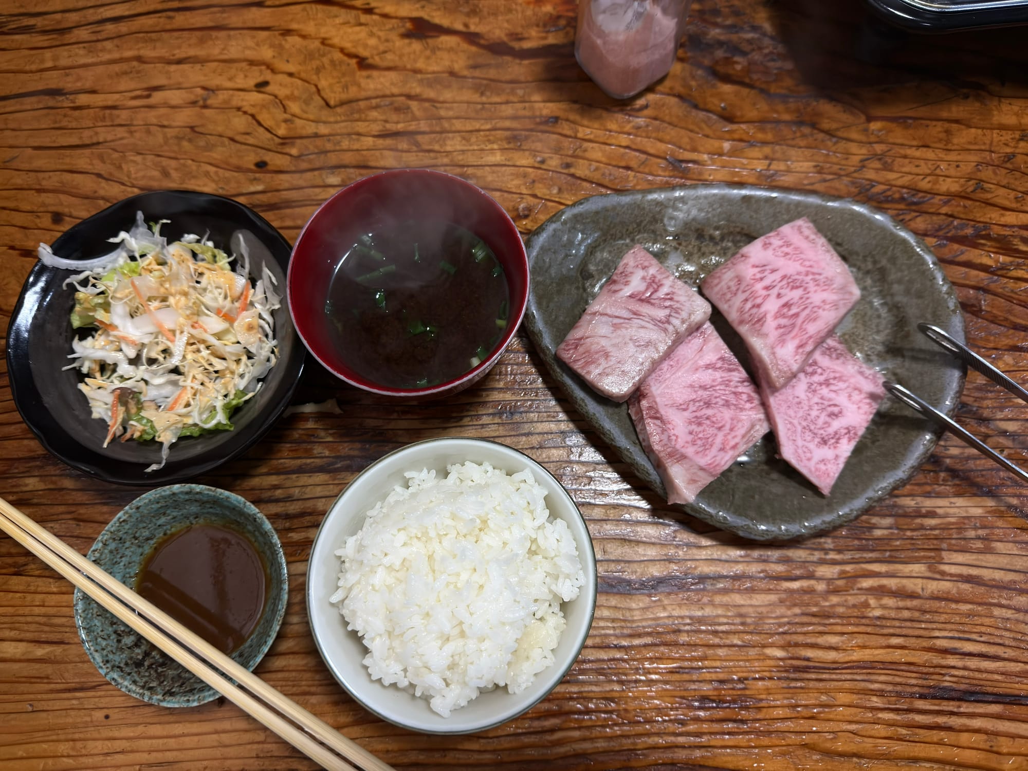 焼肉とステーキの店 初栄的高千穗牛燒肉定食套餐全貌，包含生牛肉塊、白飯、湯品與沙拉小菜。