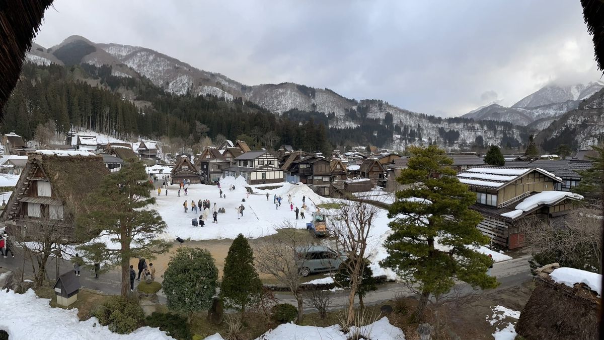 日本合掌村冬季雪景全貌，遠方是連綿山脈