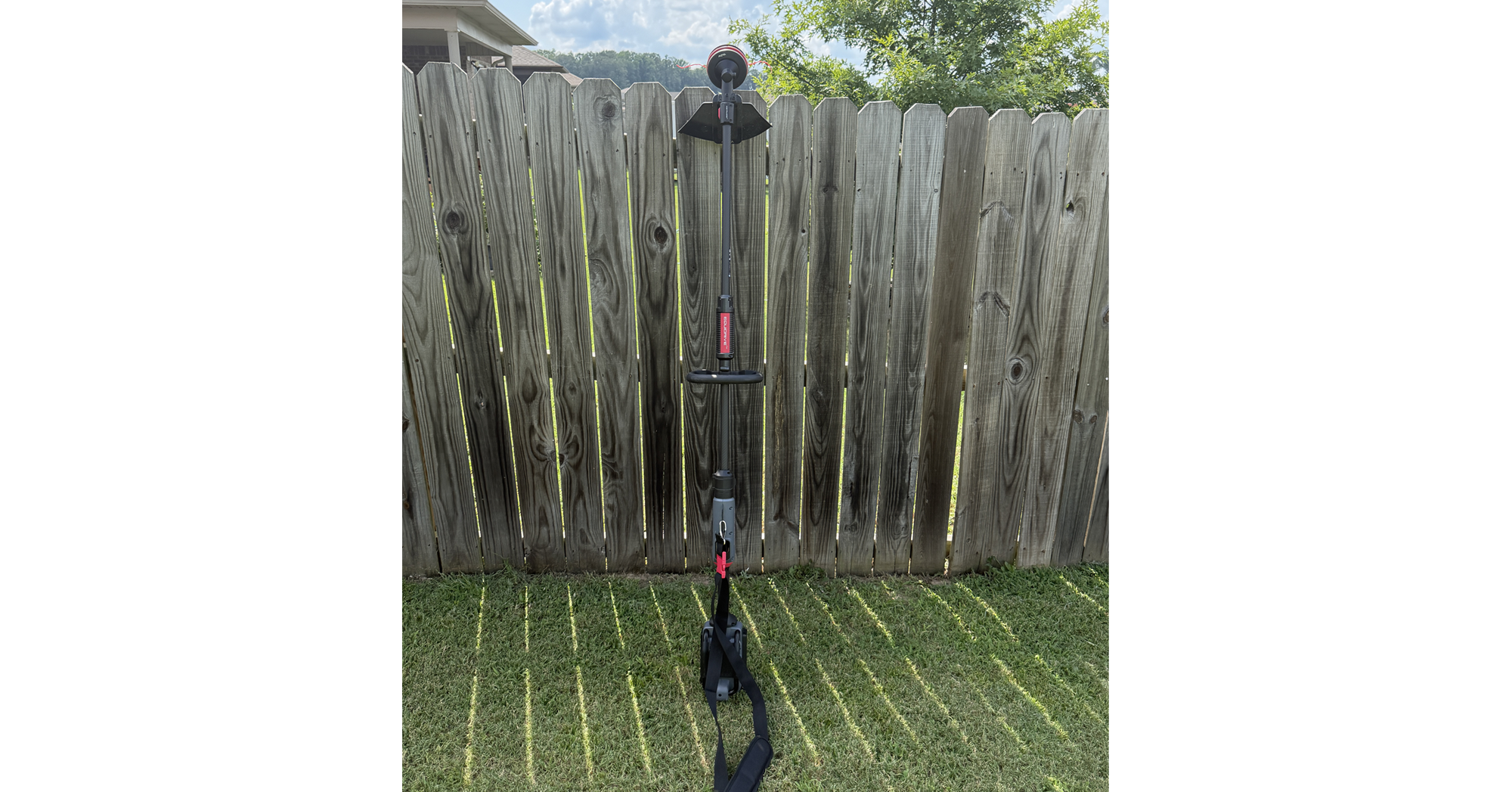 Fully assembled MOVA 16-inch string trimmer standing against a wooden fence