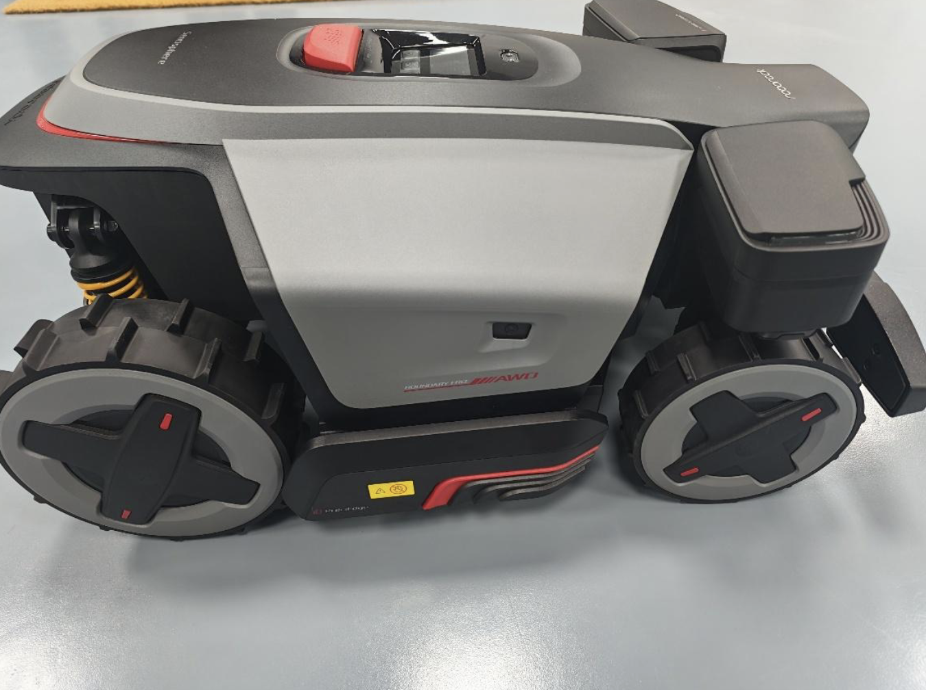 Side view of the Roborock RRAR5MON robotic lawn mower with large wheels, suspension and cutting deck.