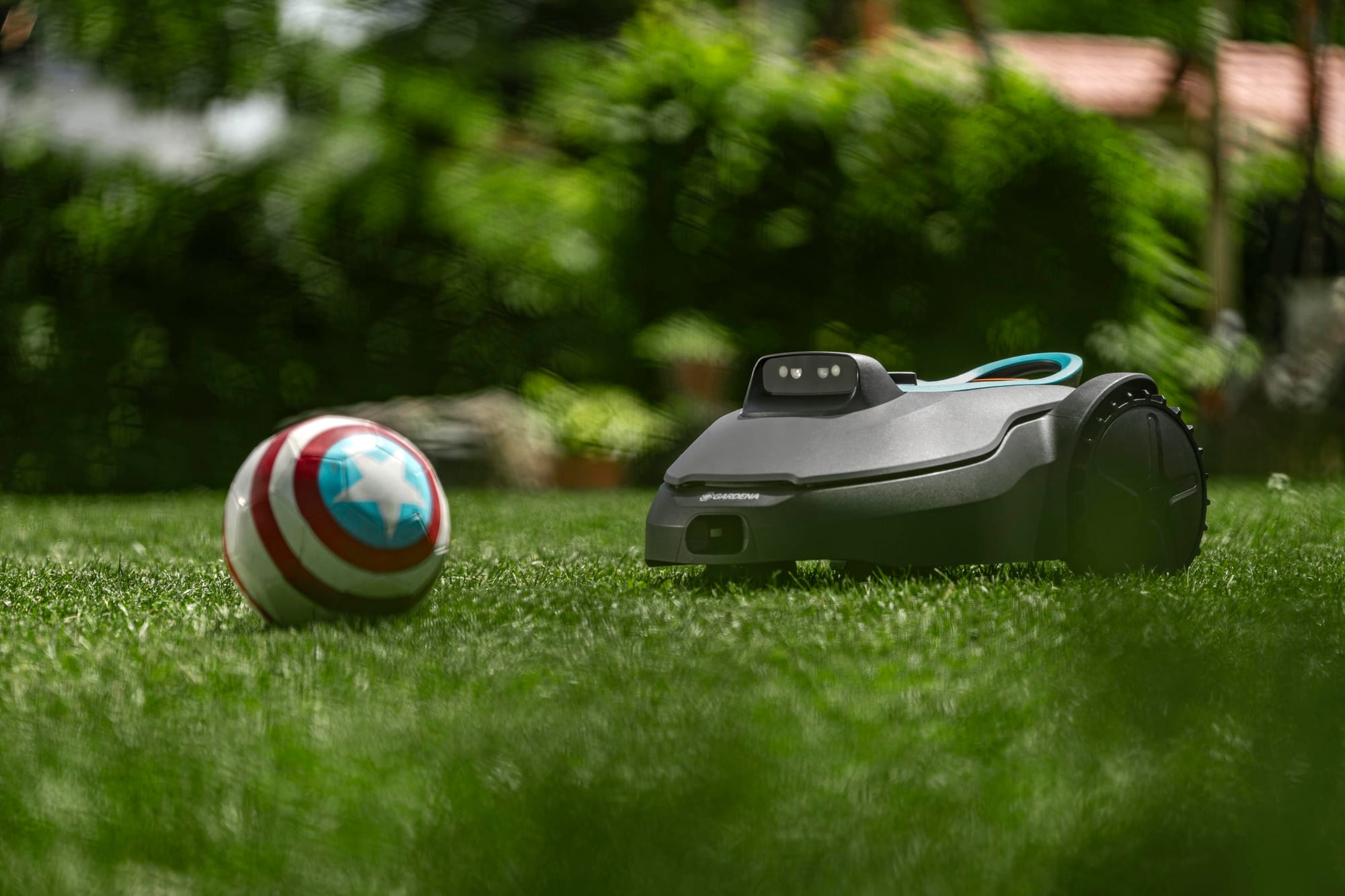 Gardena Sileno Evolve robotic lawn mower approaching a ball on a grassy lawn.