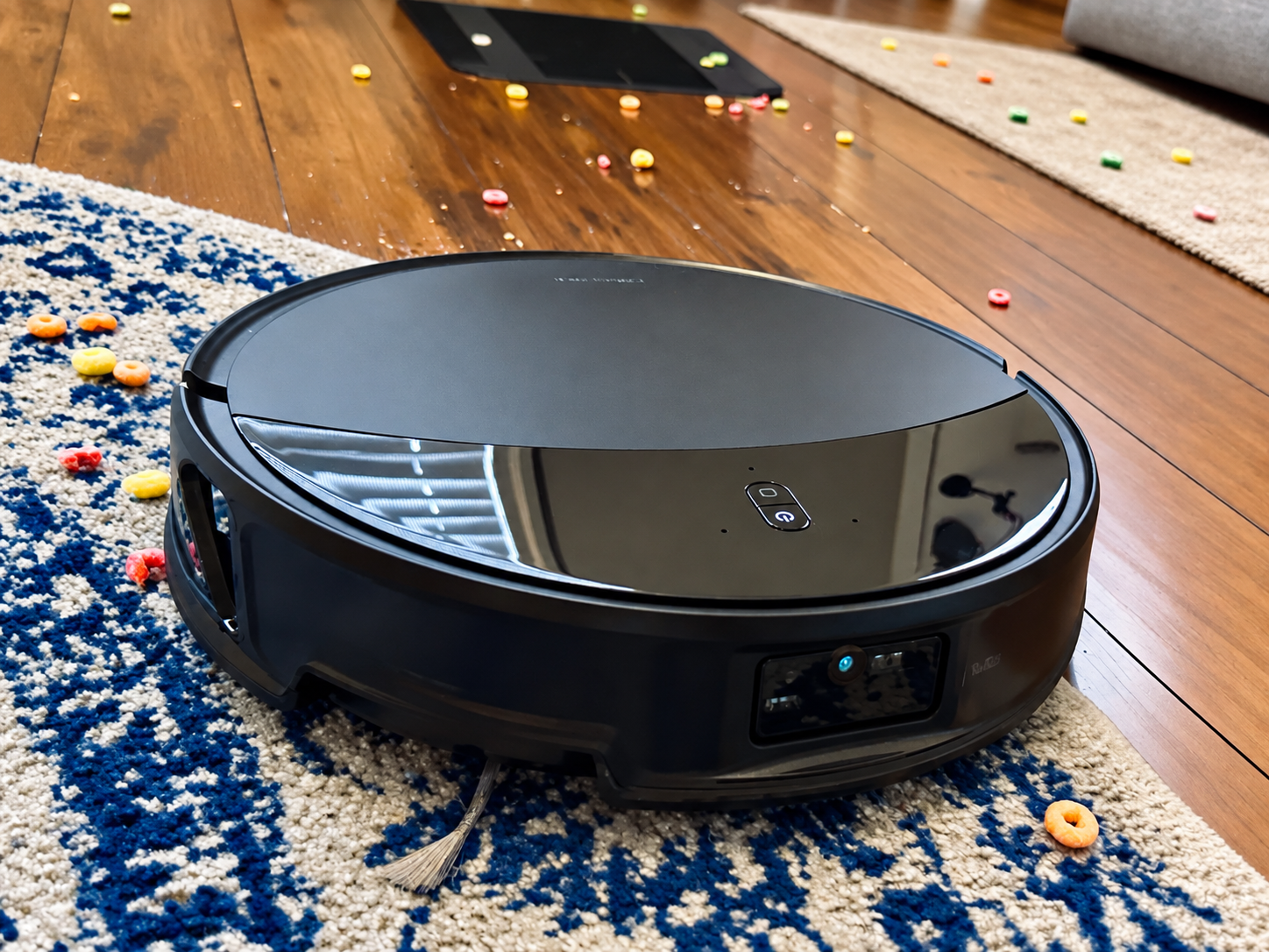 Roborock Saros 20 robot vacuum on a blue-and-white rug surrounded by colorful ring-shaped cereal pieces.