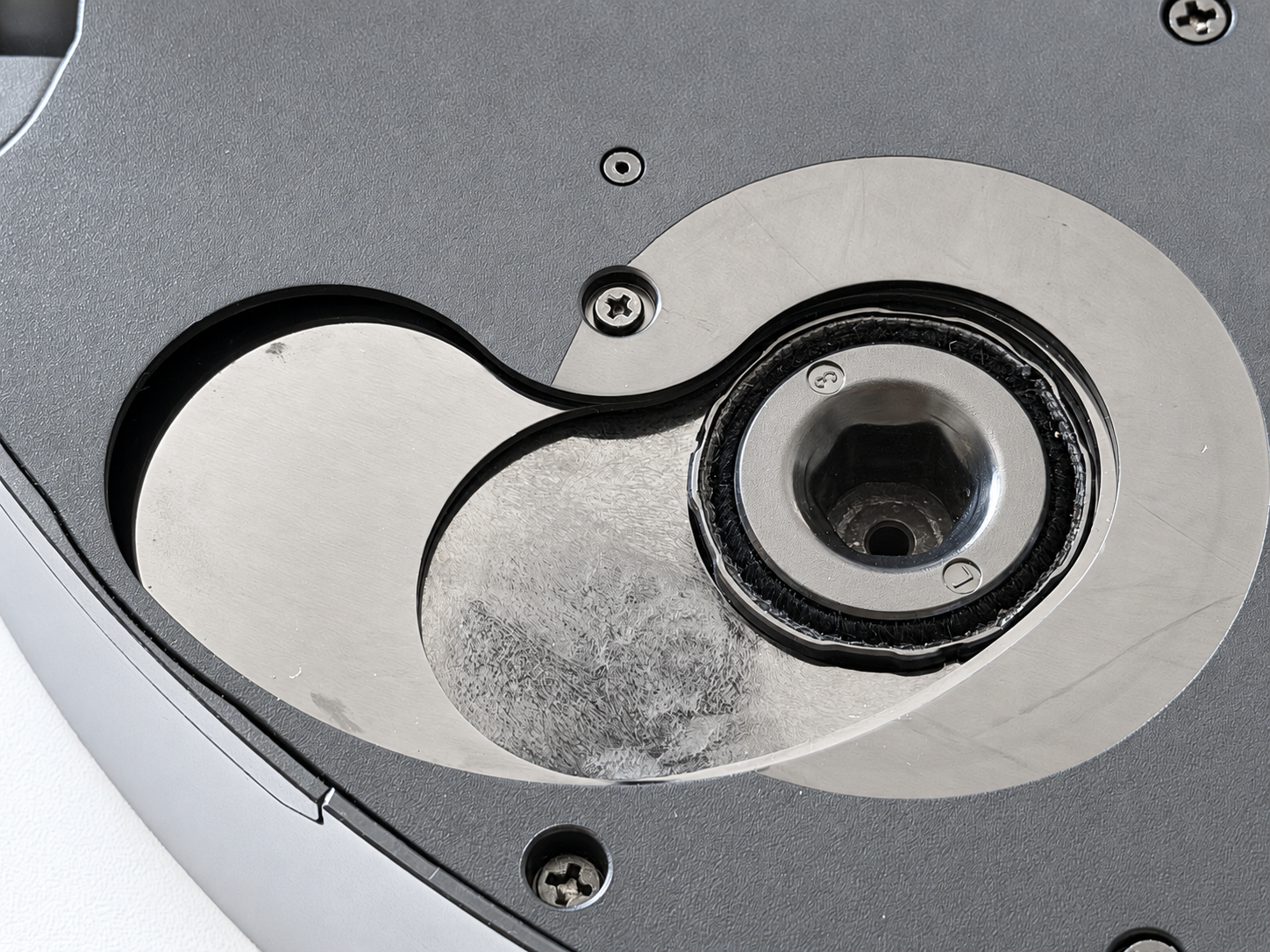 Close-up of the Dreame X60 Max Ultra Complete's extending mop mechanism on the underside of the robot, showing the circular mop mount and sliding extension arm with the mop pad removed.