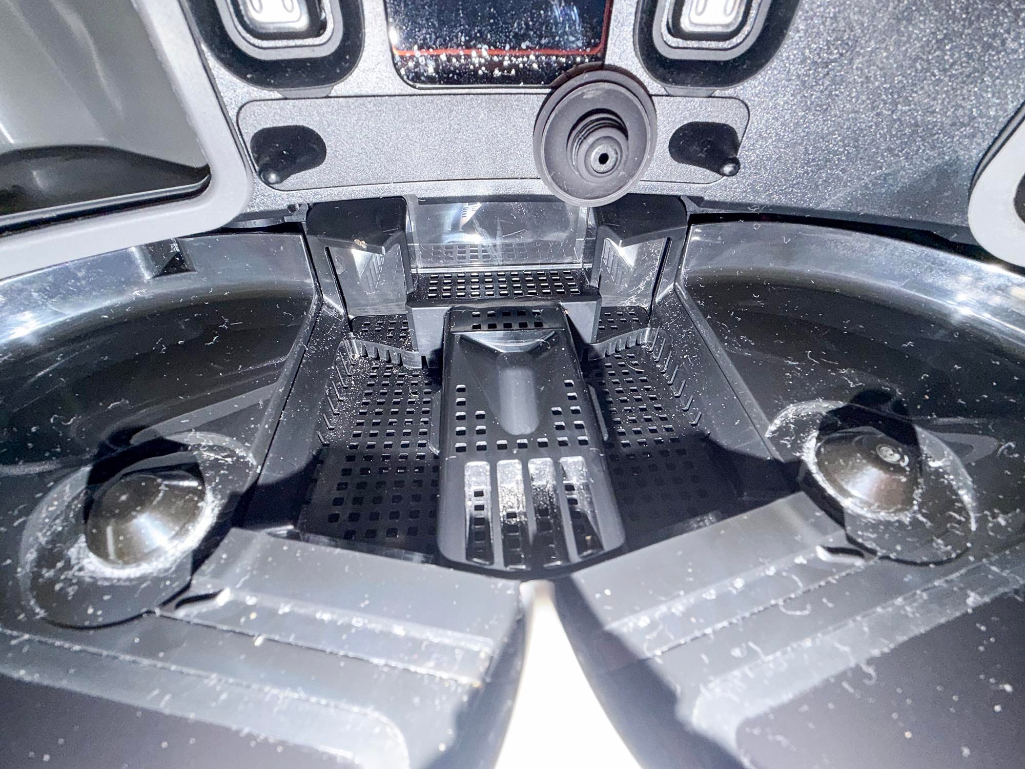 Close-up of the Dreame dock’s wash tray, showing perforated sections and residue on the black plastic surfaces.
