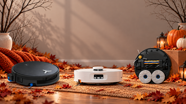 Three robot vacuums surrounded by fallen autumn leaves, bare branches, pumpkins and lanterns in a late-fall indoor setting.