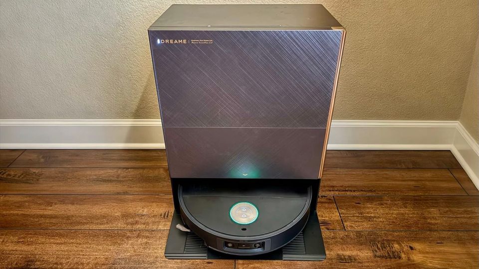Dreame X60 Max Ultra Complete robot vacuum in its rectangular dock on a wood floor against a beige wall.