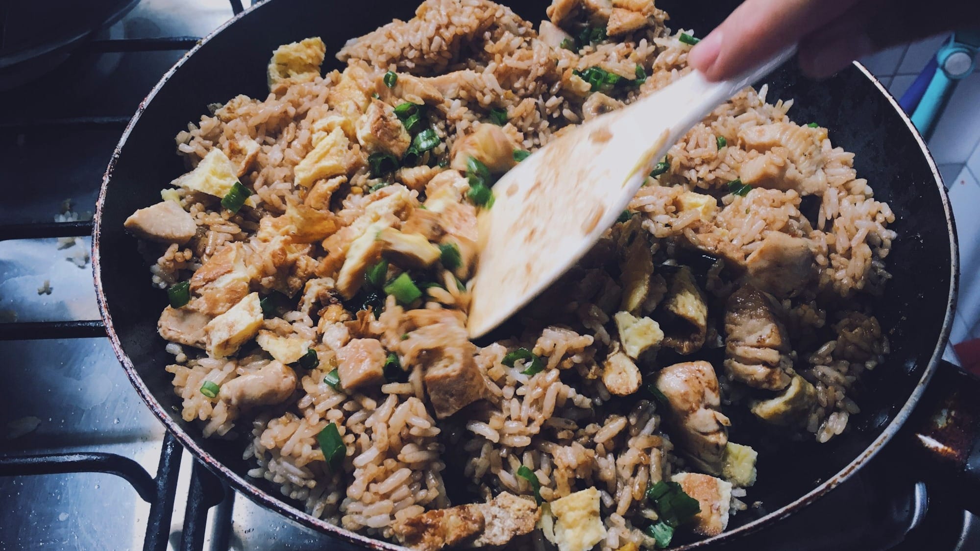 person holding black frying pan with fried rice