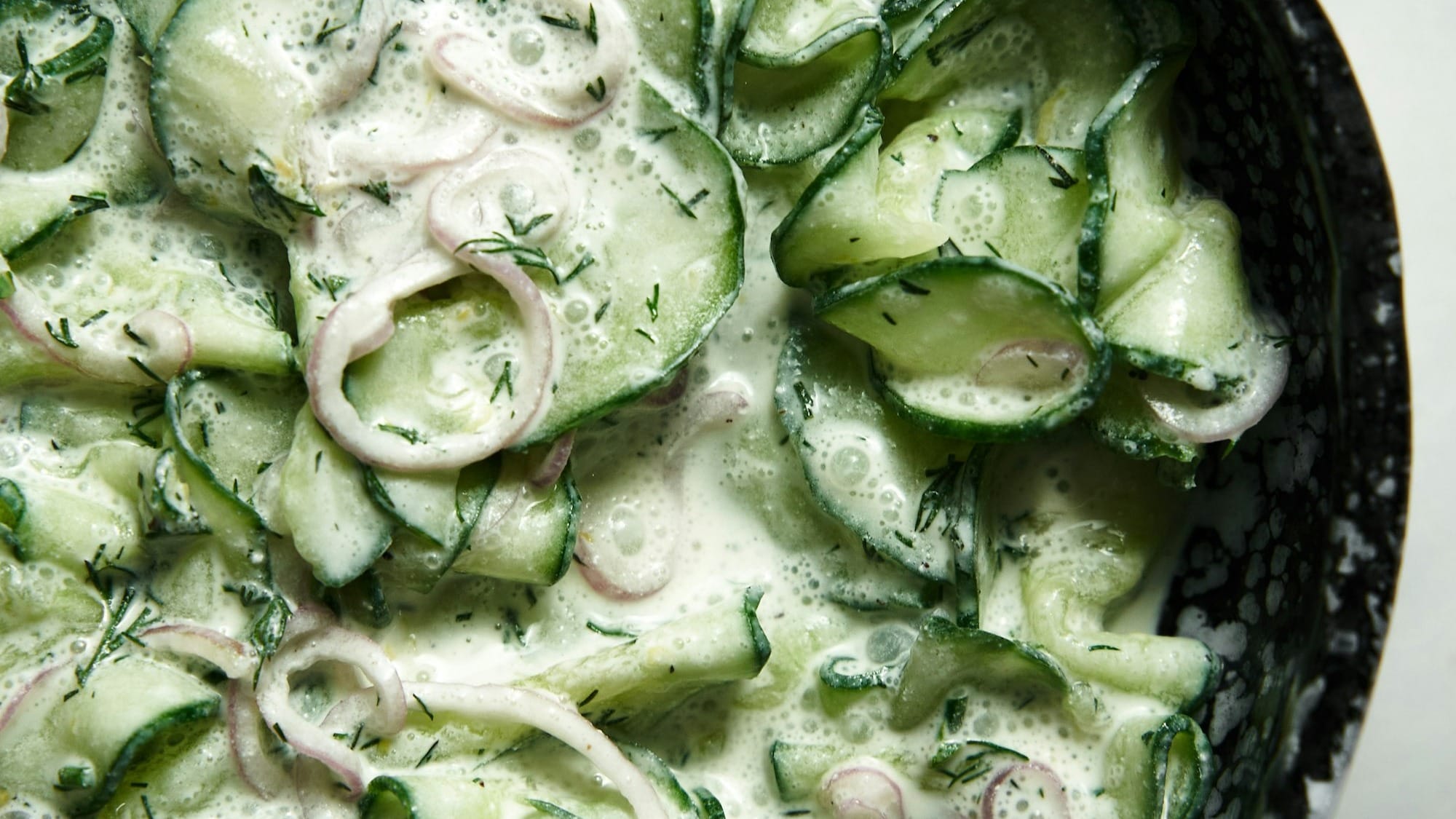 a bowl of cucumbers and onions on a table