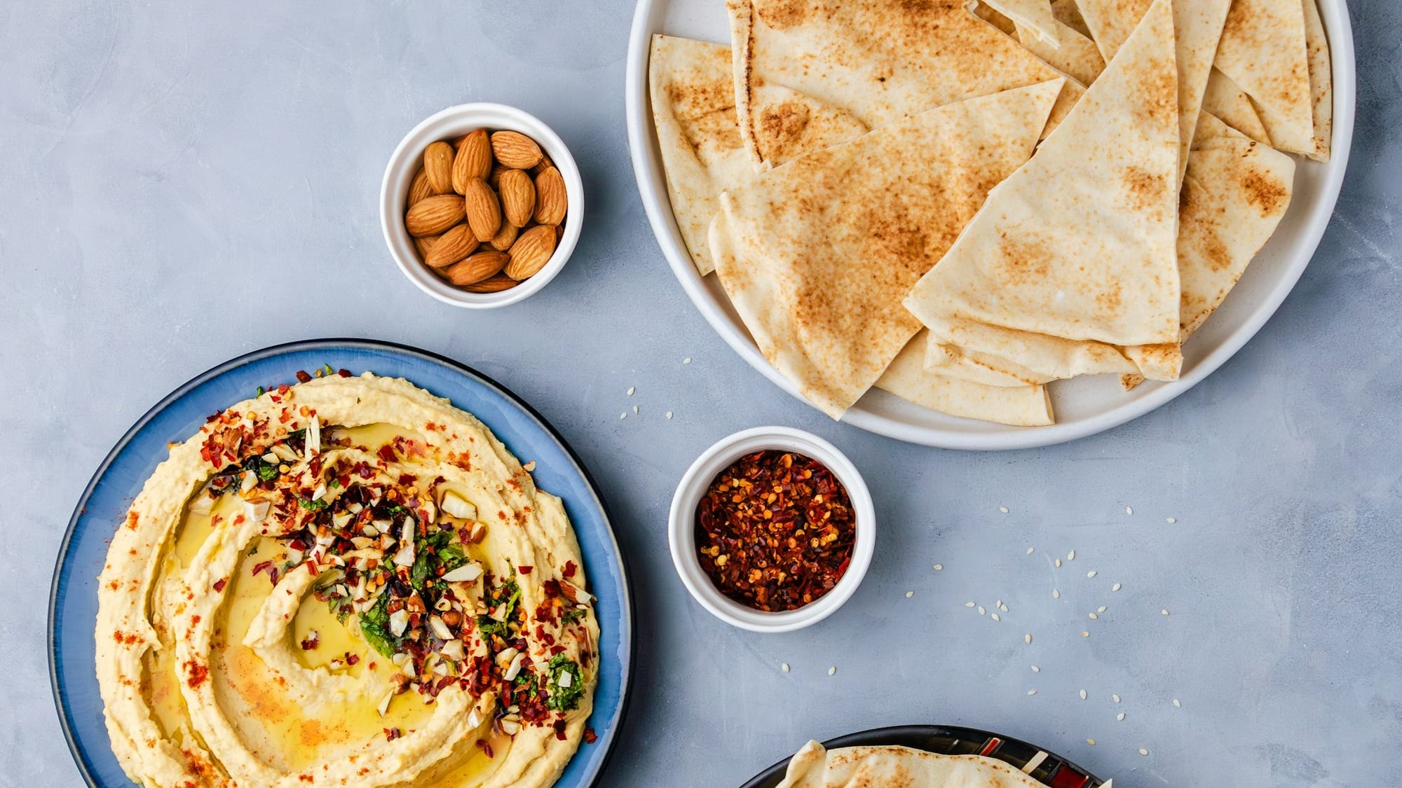 a plate of hummus, pita bread, and a bowl of hummus