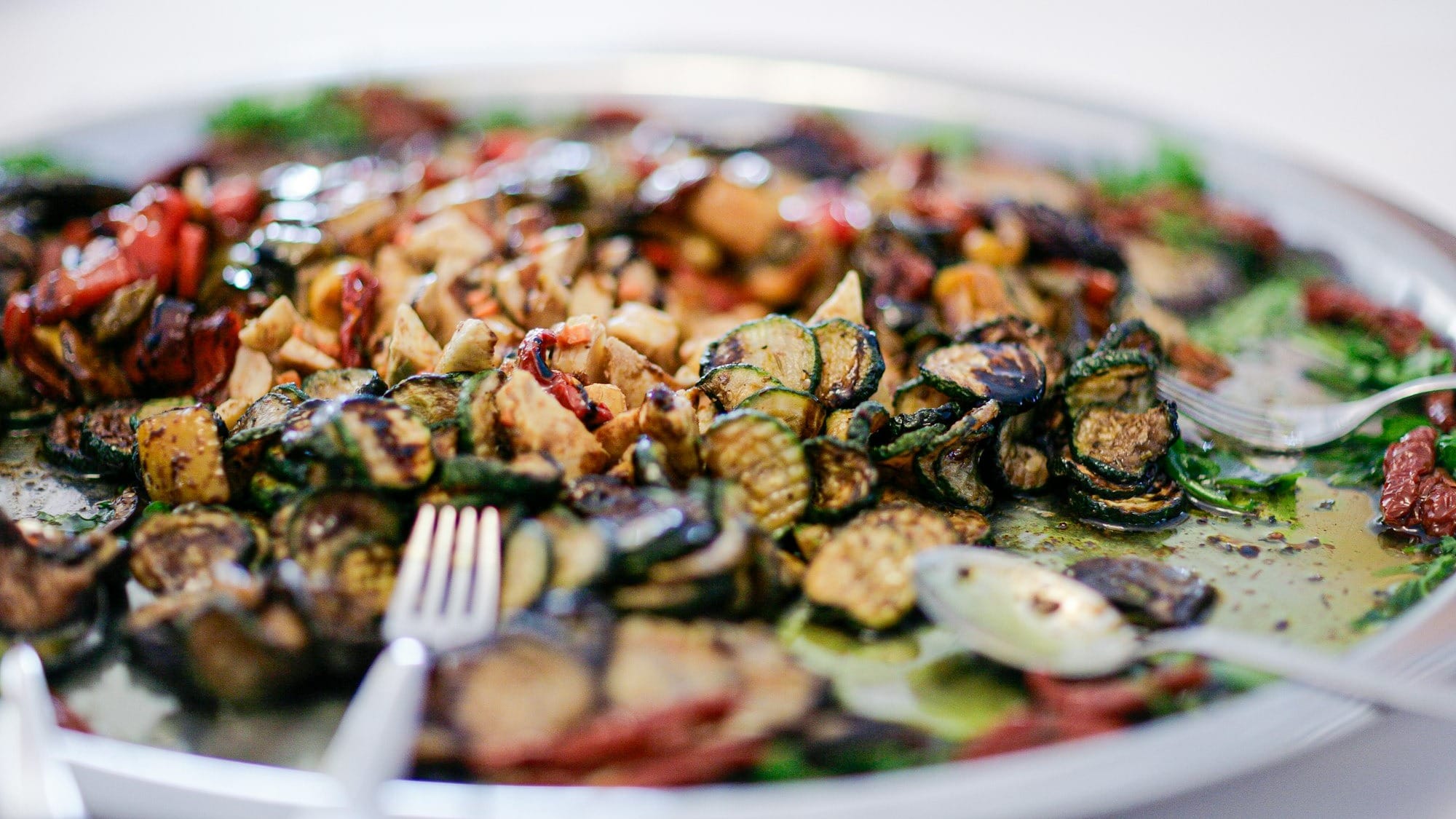 A platter of grilled vegetables with herbs and nuts.