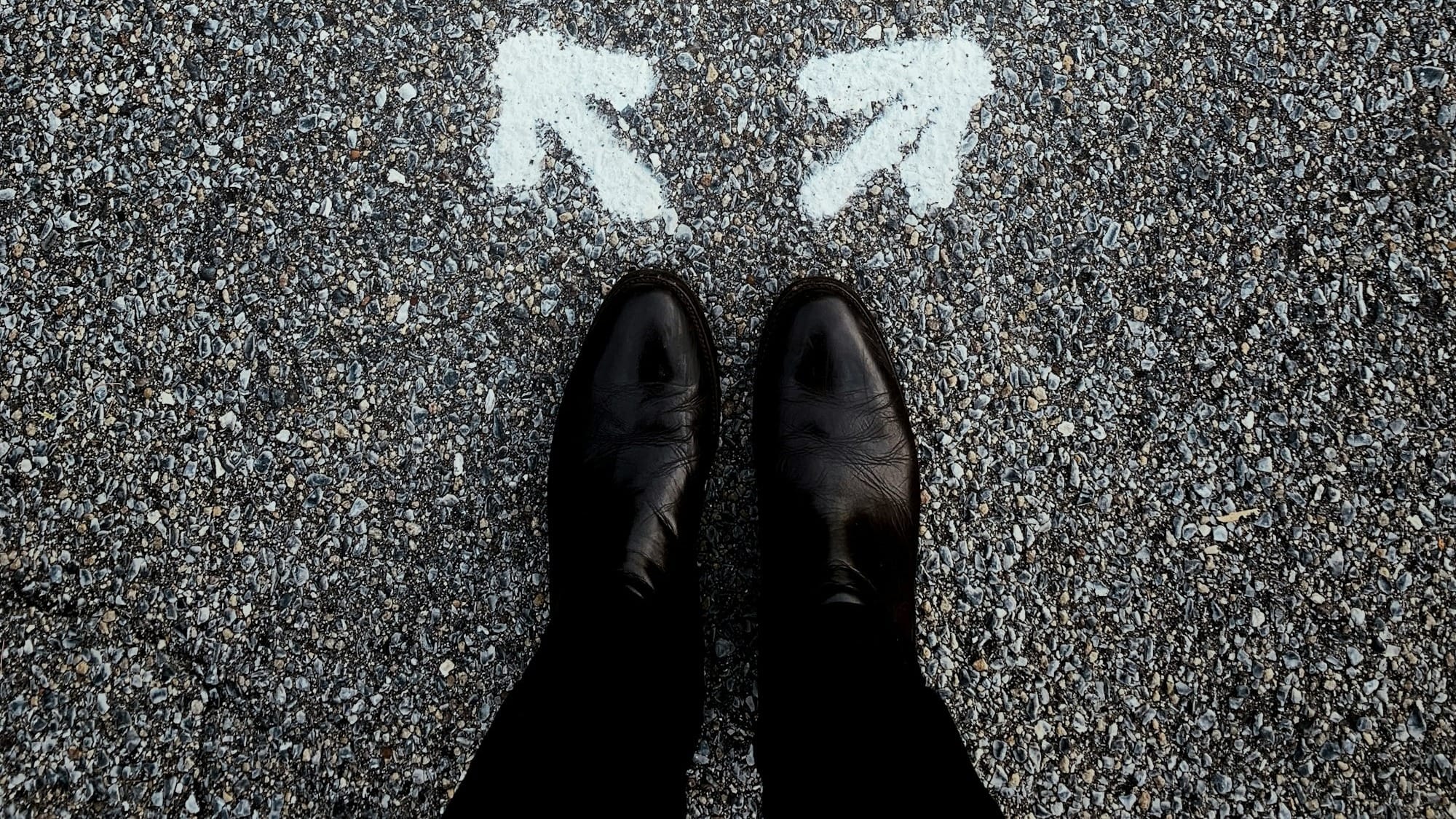 Feet on asphalt between two directional arrows.