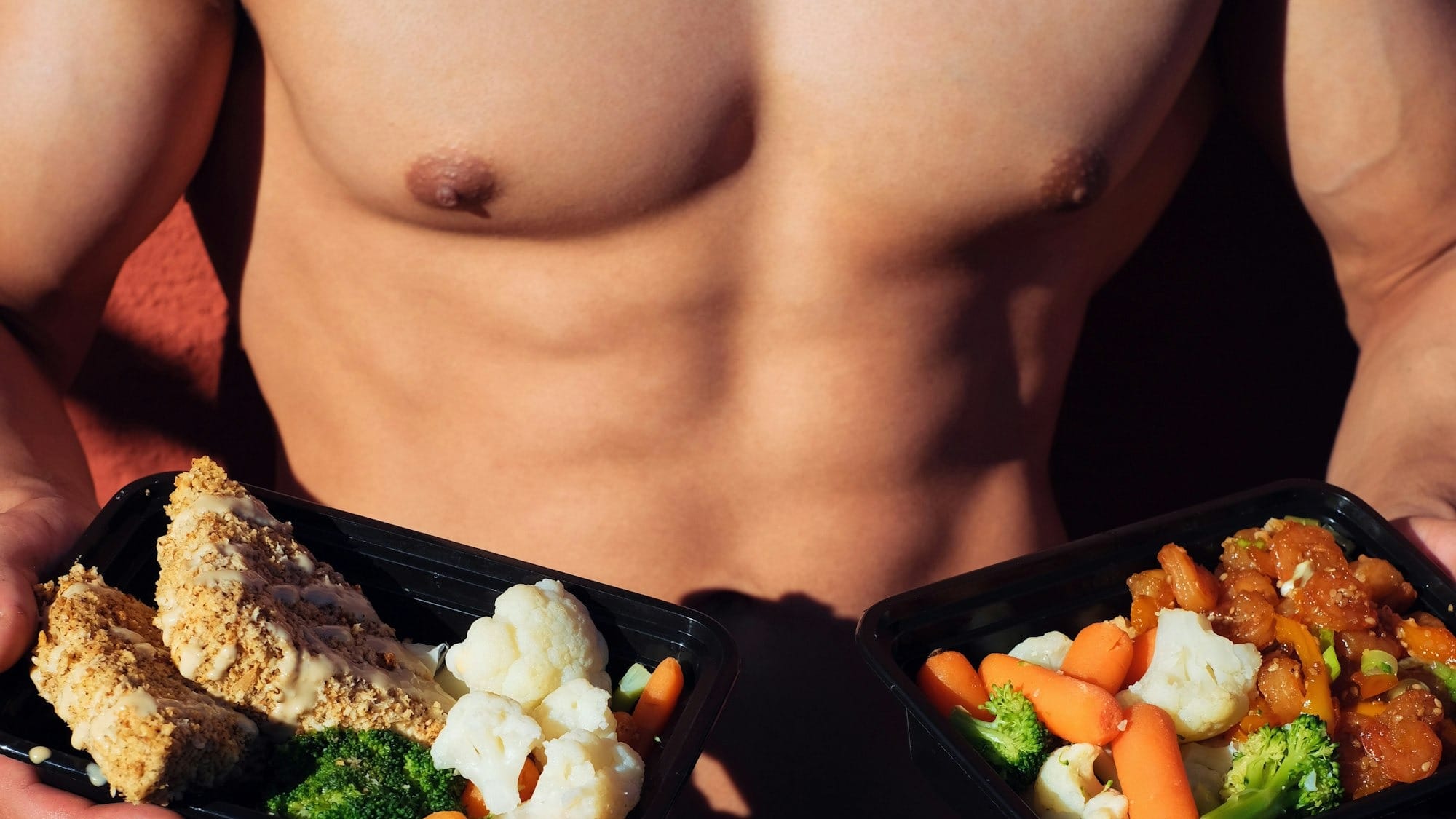 Topless man in black shorts holding cooked food.