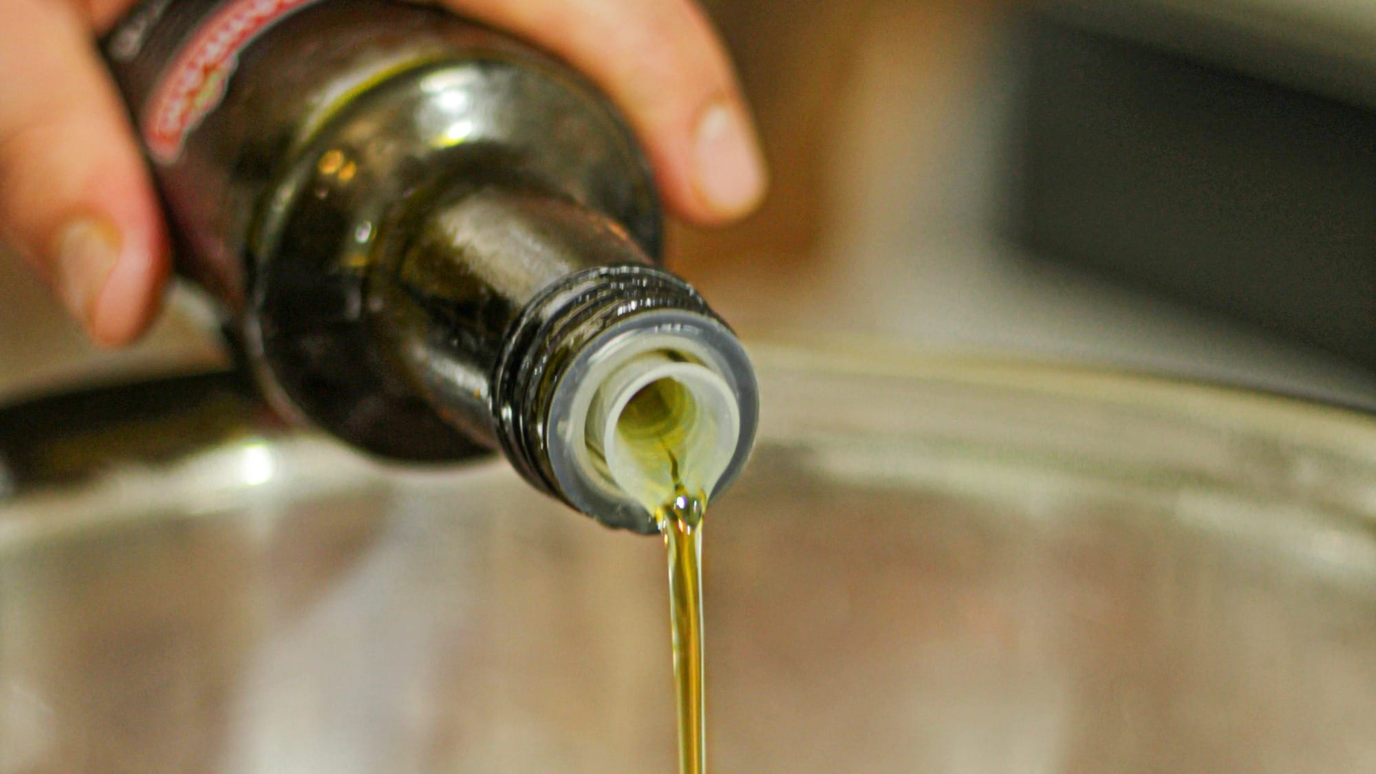 A person pouring olive into a pot.