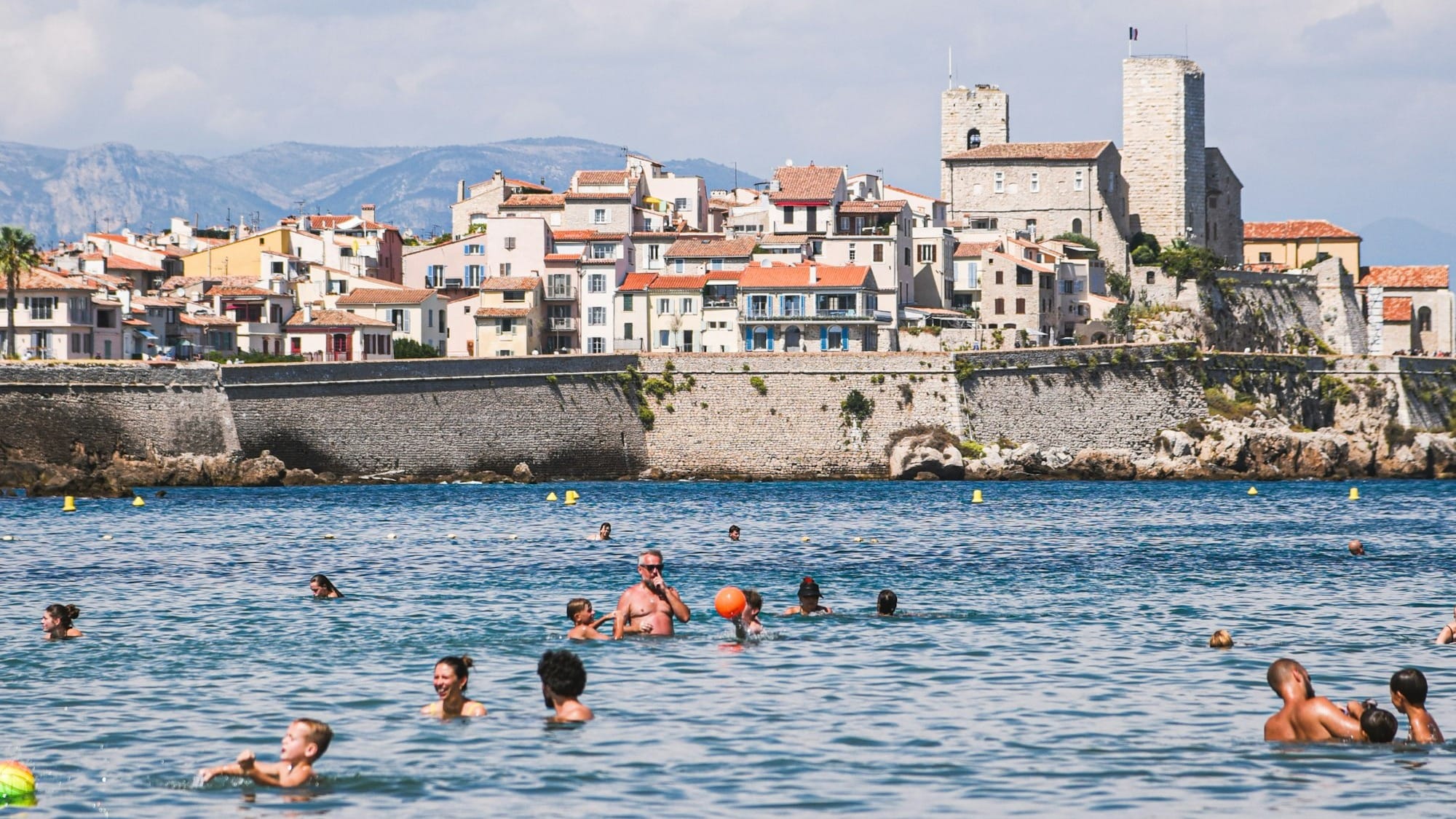 People swimming in the sea with a coastal town behind.