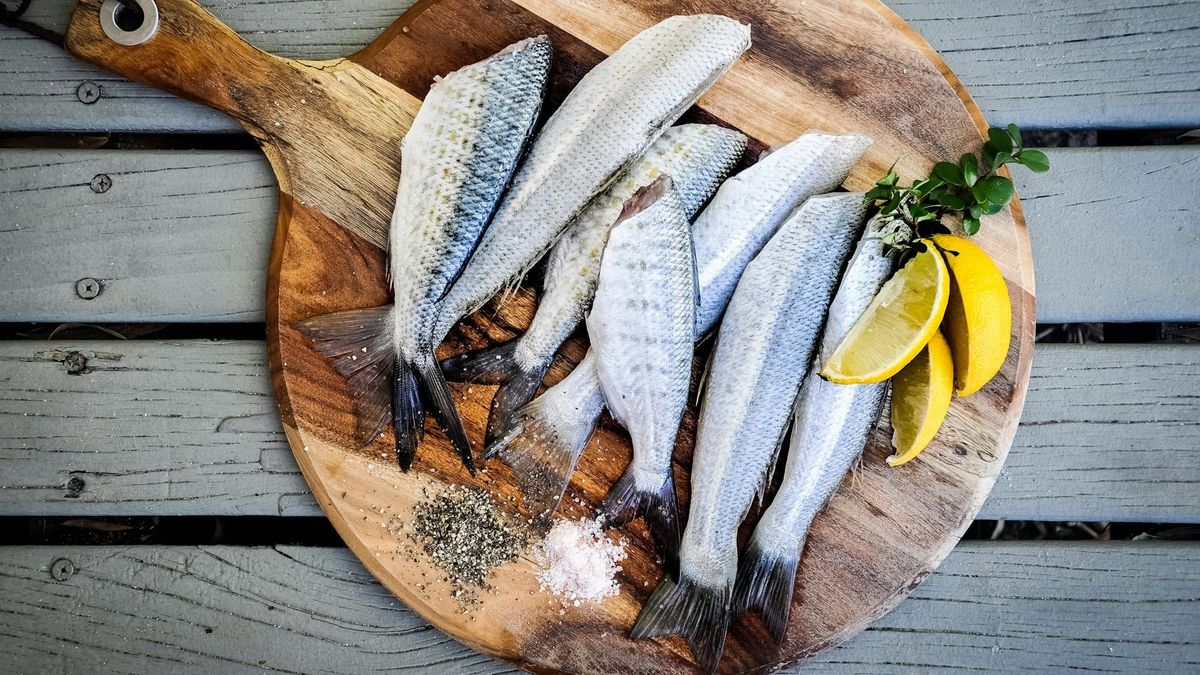 Oily fish and lemons on a wood board.