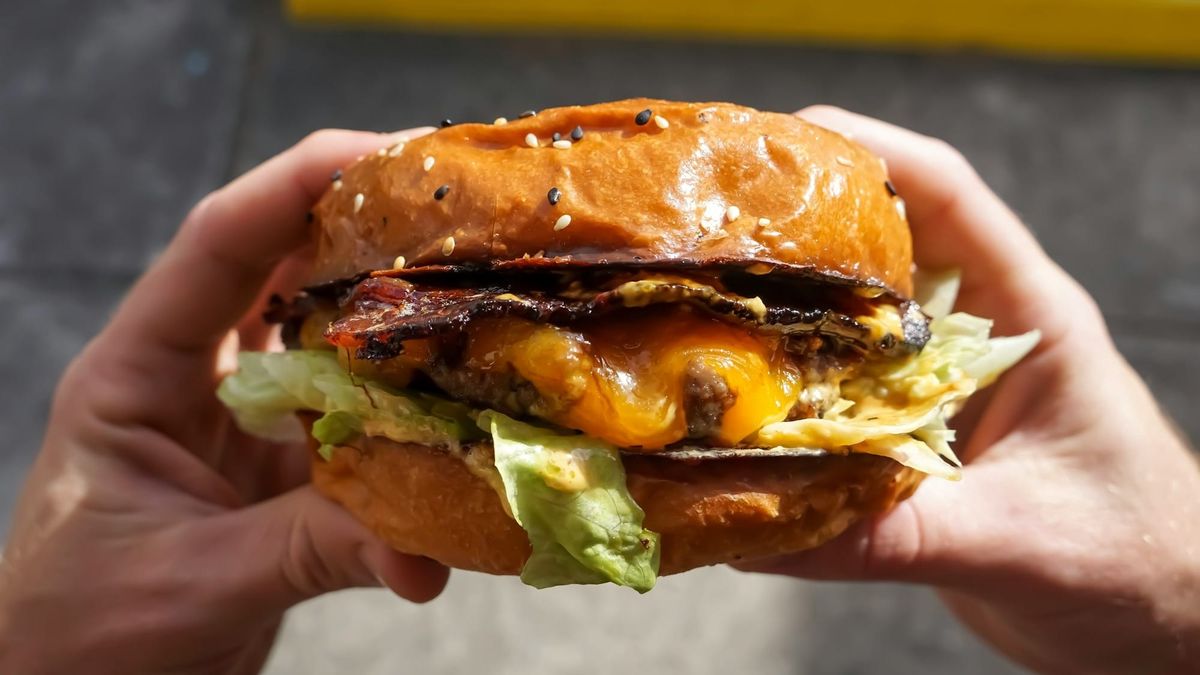Person holding a cheeseburger.