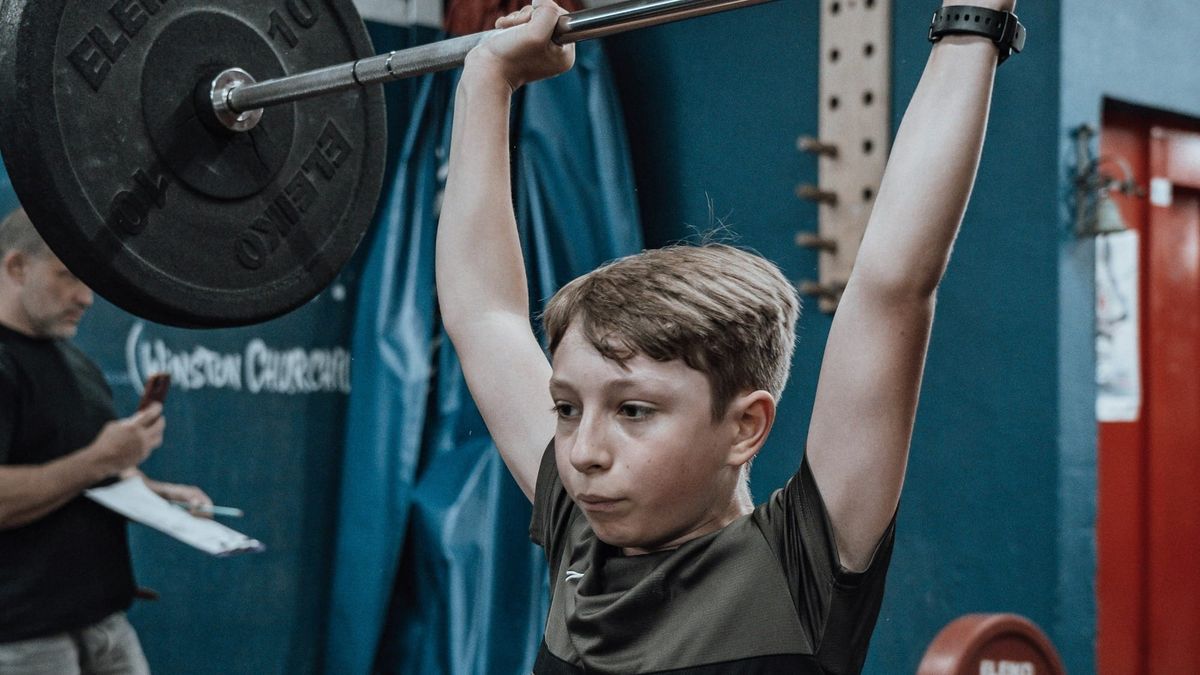 Young boy lifting weight above his head.