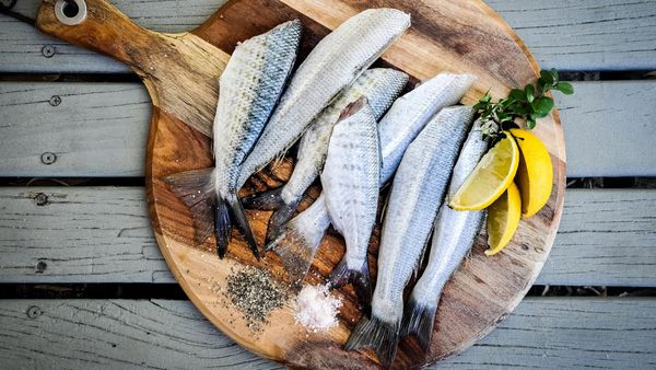 Oily fish and lemons on a wood board.