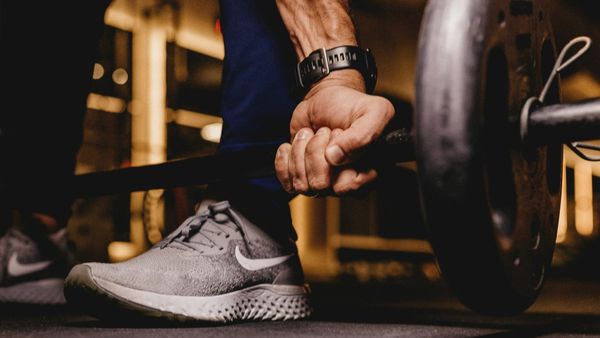 Person with watch barbell deadlifting in the gym.