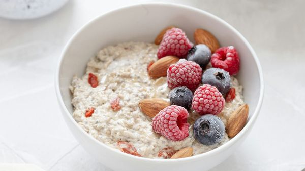 Bowl of porridge with red berries and almonds.