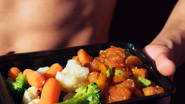 Man holding a balanced meal in a black container