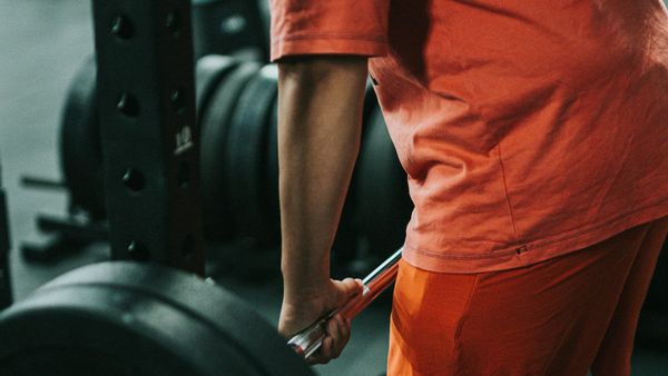 Person in orange t-short lifting a barbell