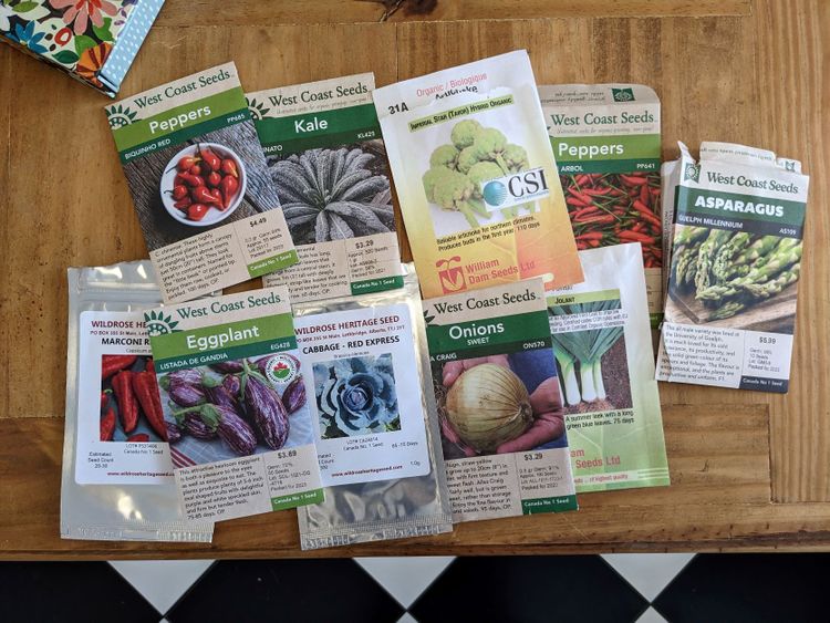 Miscellaneous colorful seed packets arranged on a wood table. 