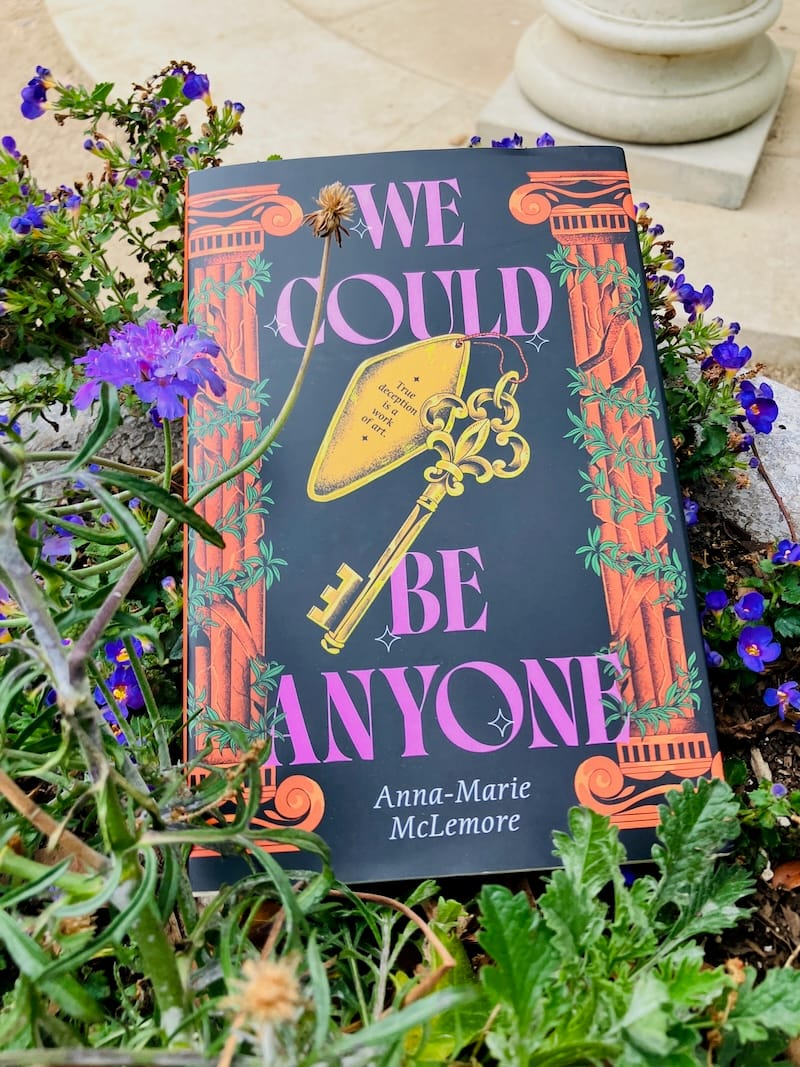 Hardcover of Anna-Marie McLemore’s We Could Be Anyone among vining plants with purple flowers.