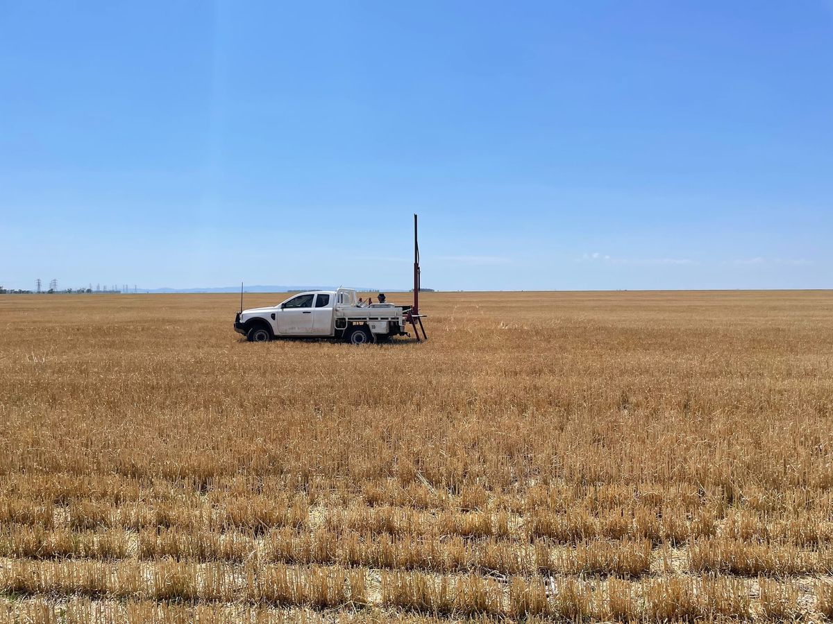 A ute in the middle of a vast, harvested wheat field with a soil sampling machine in the tray.