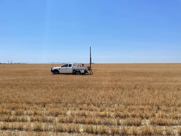 A ute in the middle of a vast, harvested wheat field with a soil sampling machine in the tray.