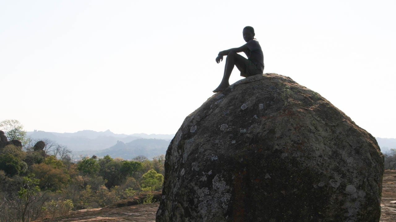 a child sitting on a large boulder, Matopo Hills in Zimbabwe
