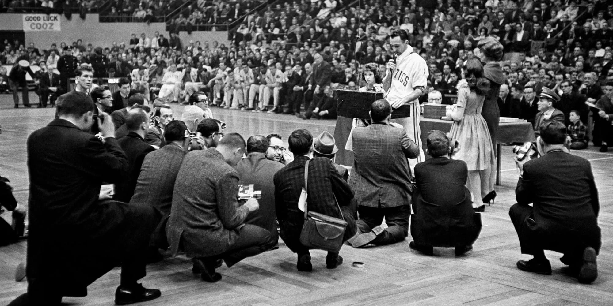 Cousy at the microphone at his Boston Garden farewell in March 1963, under a "GOOD LUCK COOZ" banner.