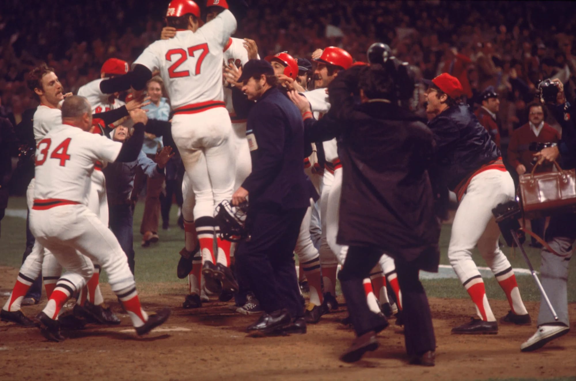 The Red Sox mob Fisk at the plate.