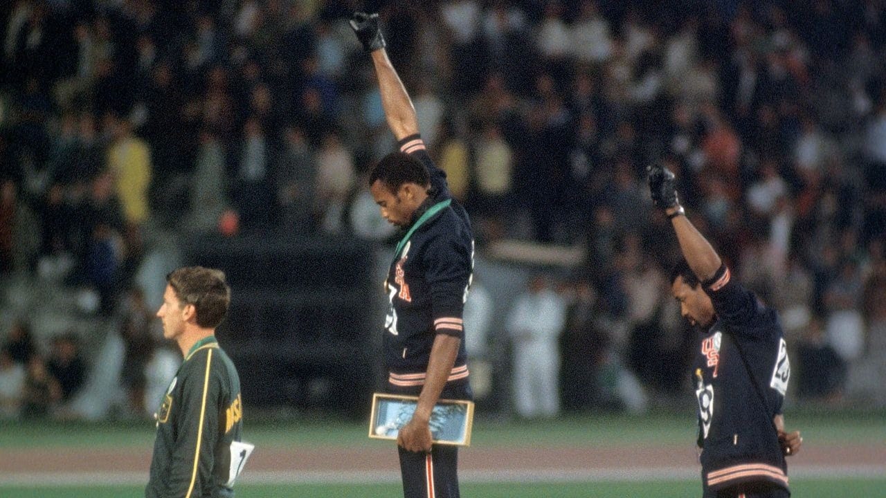 Tommie Smith (center) and John Carlos (right) during the national anthem, Oct. 16, 1968. Peter Norman of Australia, silver medalist, wears the Olympic Project for Human Rights badge on his left breast.