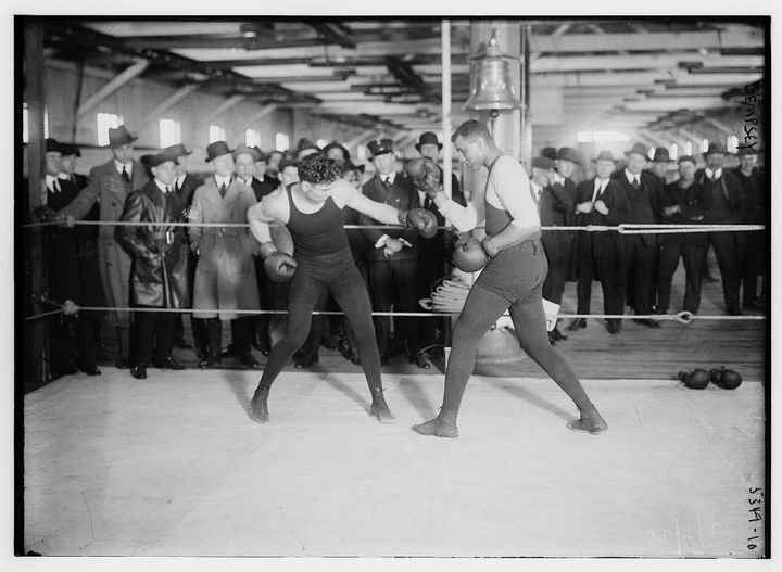 Jack Dempsey sparring in a gym ring in 1920, spectators lining the ropes